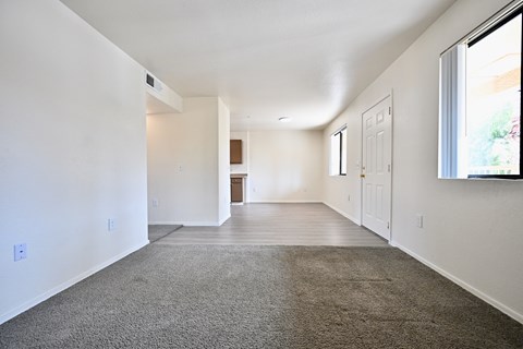 A spacious room with a carpeted floor and white walls.