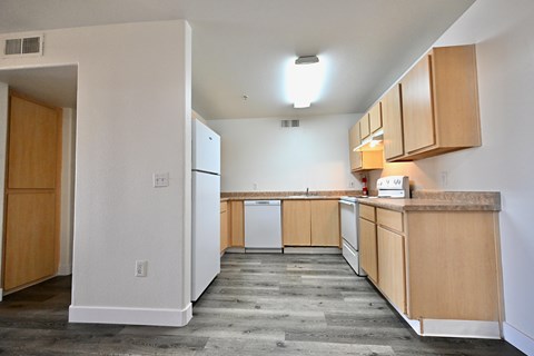 A kitchen with white walls and wooden cabinets.