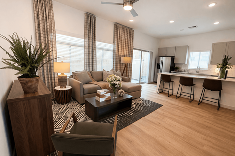A living room with a brown sofa, a wooden side table, and a black and white patterned rug.