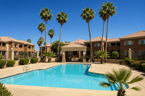 A swimming pool surrounded by palm trees and apartment buildings.