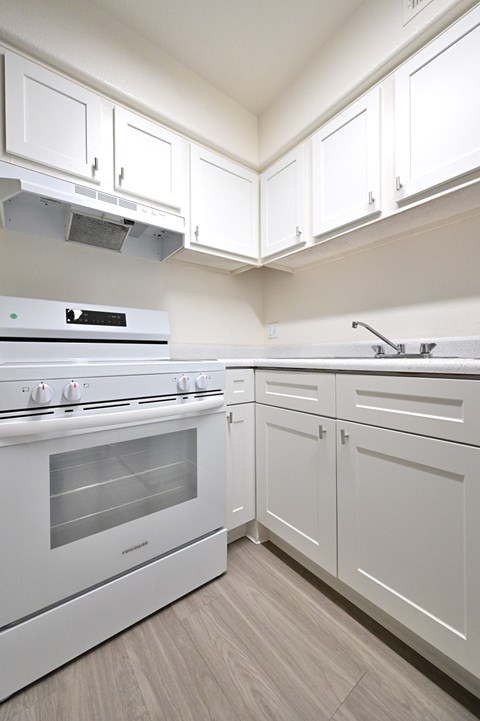 A white kitchen with a stove and cabinets.