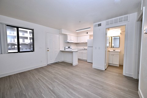 A spacious kitchen with white cabinets and a wooden floor.