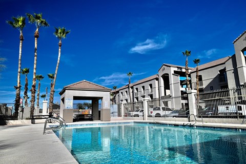 A pool with a building in the background and palm trees.