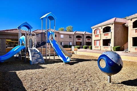 A playground with a blue slide and a blue ball.