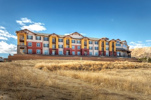 A large multi-story building with a red and yellow facade sits on a hill.
