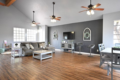 A living room with a grey couch, a white coffee table, and a TV on the wall.