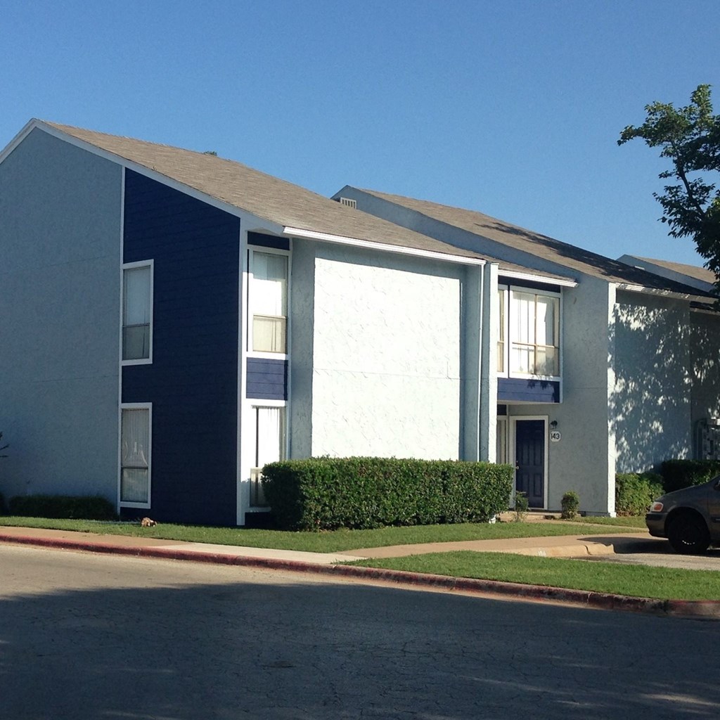 a blue and white apartment building with a car parked in front of it