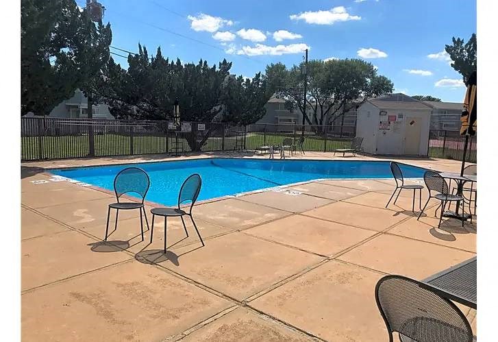 a swimming pool with chairs and tables around it