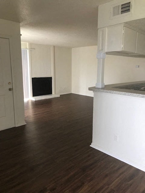 an empty living room with a fireplace and a kitchen