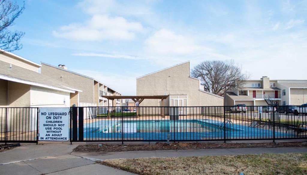 a swimming pool behind a fence in front of a building