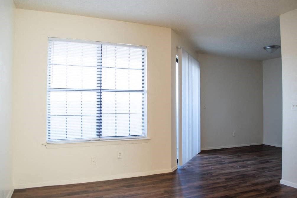 an empty room with a large window and wooden floors