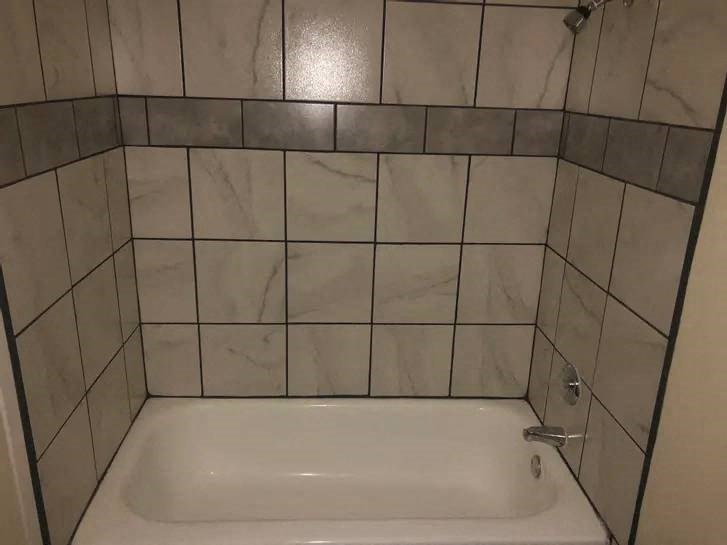 a white bath tub sitting next to a white tiled wall