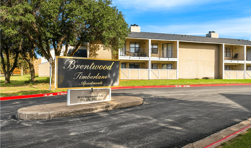 A sign for Brentwood Timberlane Apartments is displayed in front of a building.