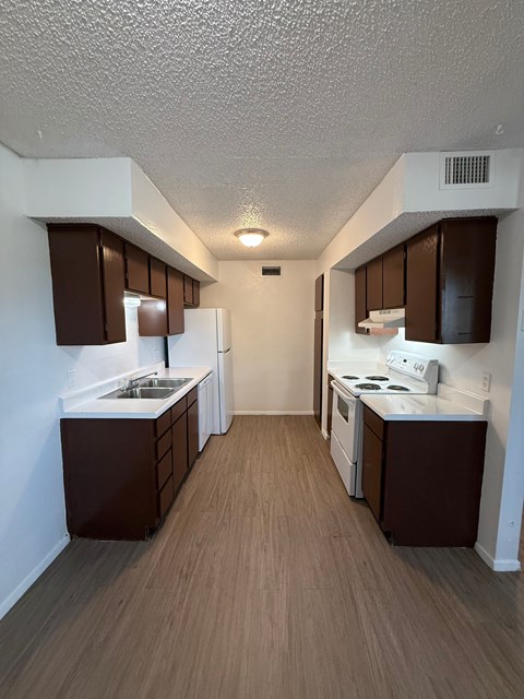 A kitchen with brown cabinets and white appliances.