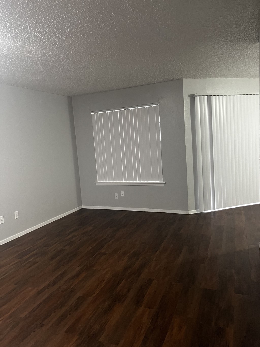 an empty living room with hardwood floors and a large window