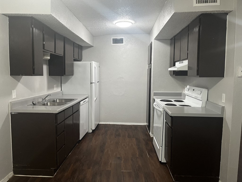 an empty kitchen with black cabinets and white appliances
