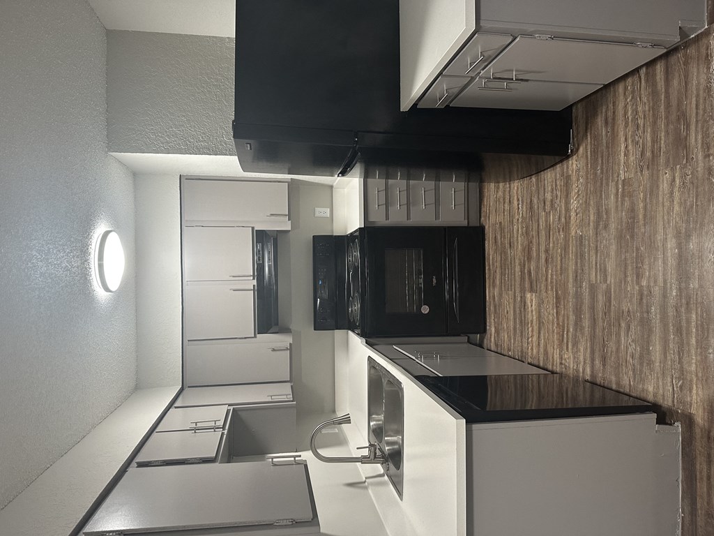 a kitchen with white cabinets and black countertops