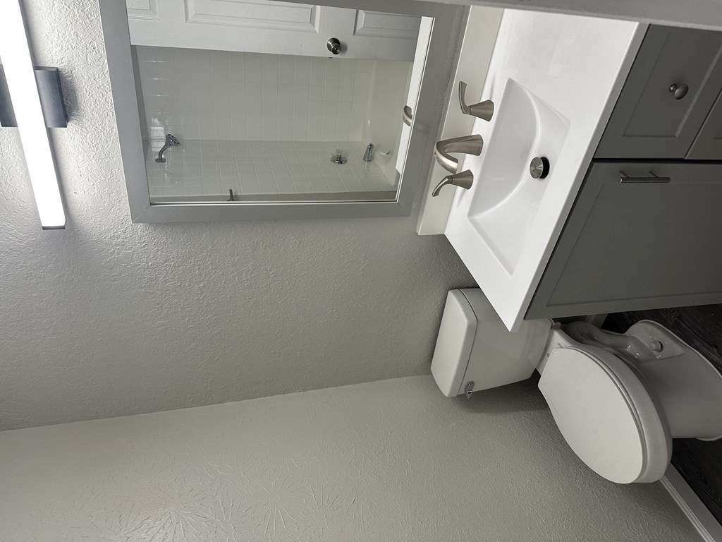 A white bathroom with a sink and mirror.