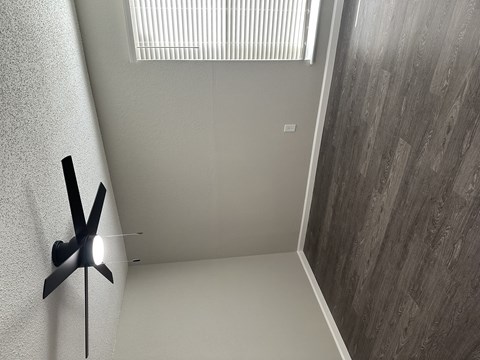 A black fan is mounted on a white wall.