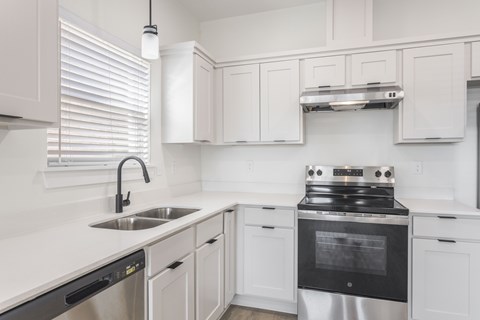 A modern kitchen with white cabinets and stainless steel appliances.