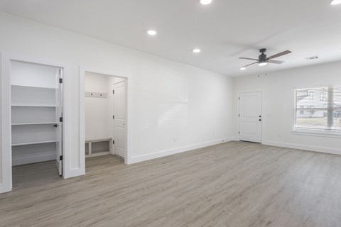 A spacious room with a ceiling fan and lighting fixtures.