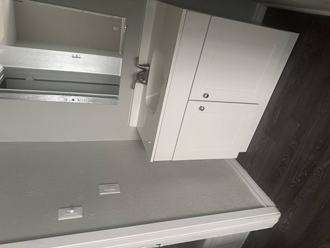 A white cabinet with a drawer and a shelf is installed in a kitchen.