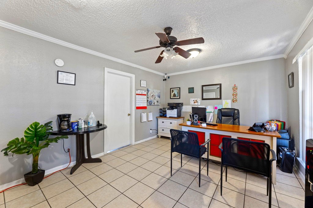 A room with a ceiling fan and a desk with a computer.