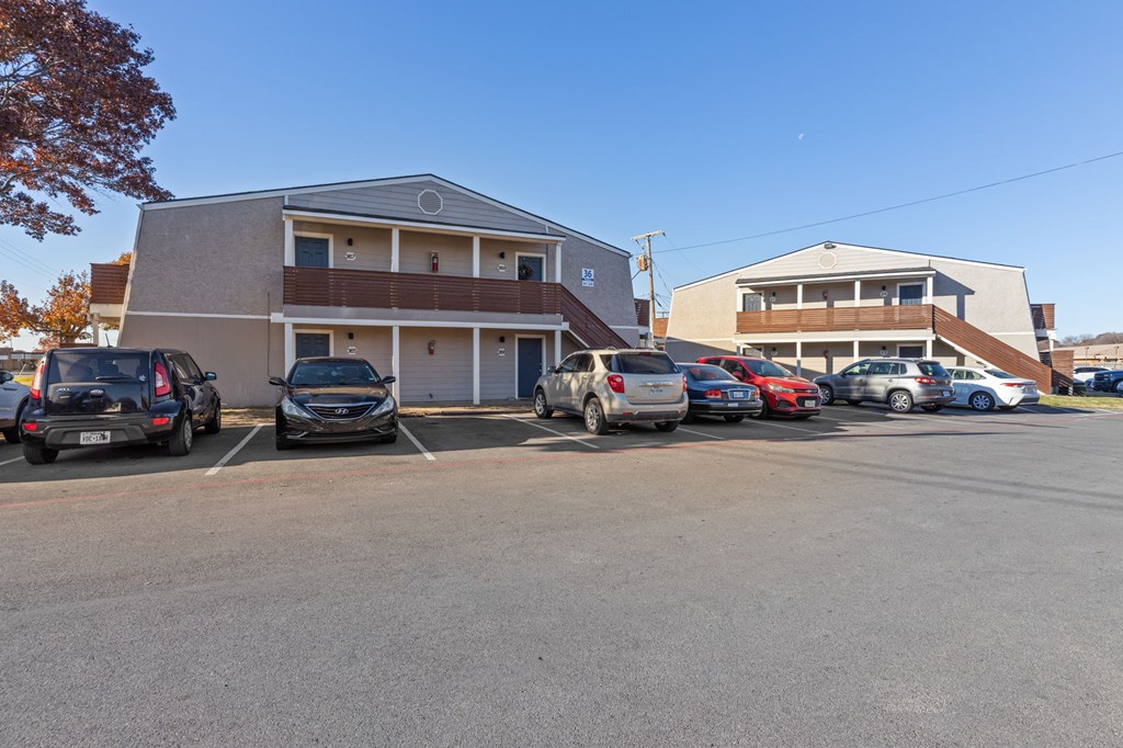 A parking lot with cars and a building in the background.