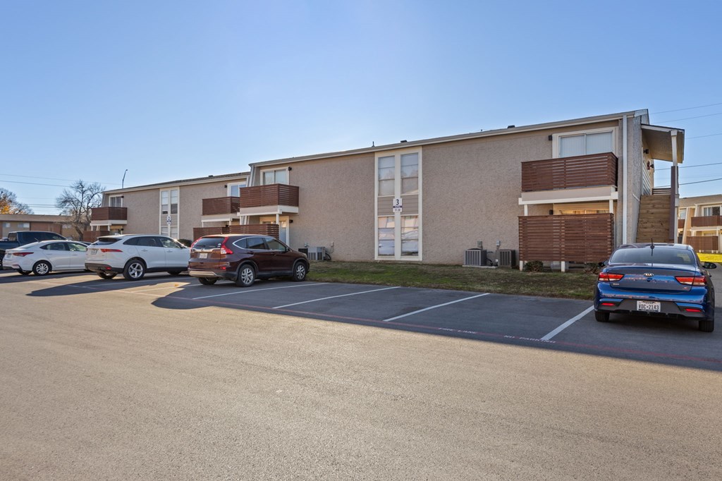 A parking lot with cars and apartment buildings in the background.