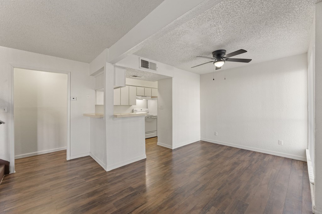 A room with a ceiling fan and wooden floors.