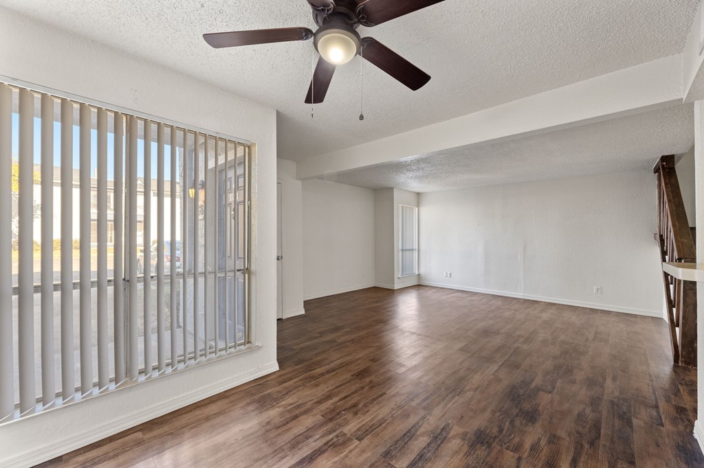 A room with a ceiling fan and wooden flooring.