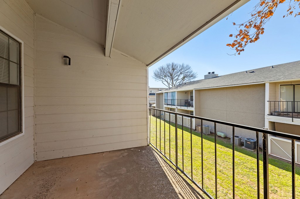 A balcony with a black railing and a small tree in the background.