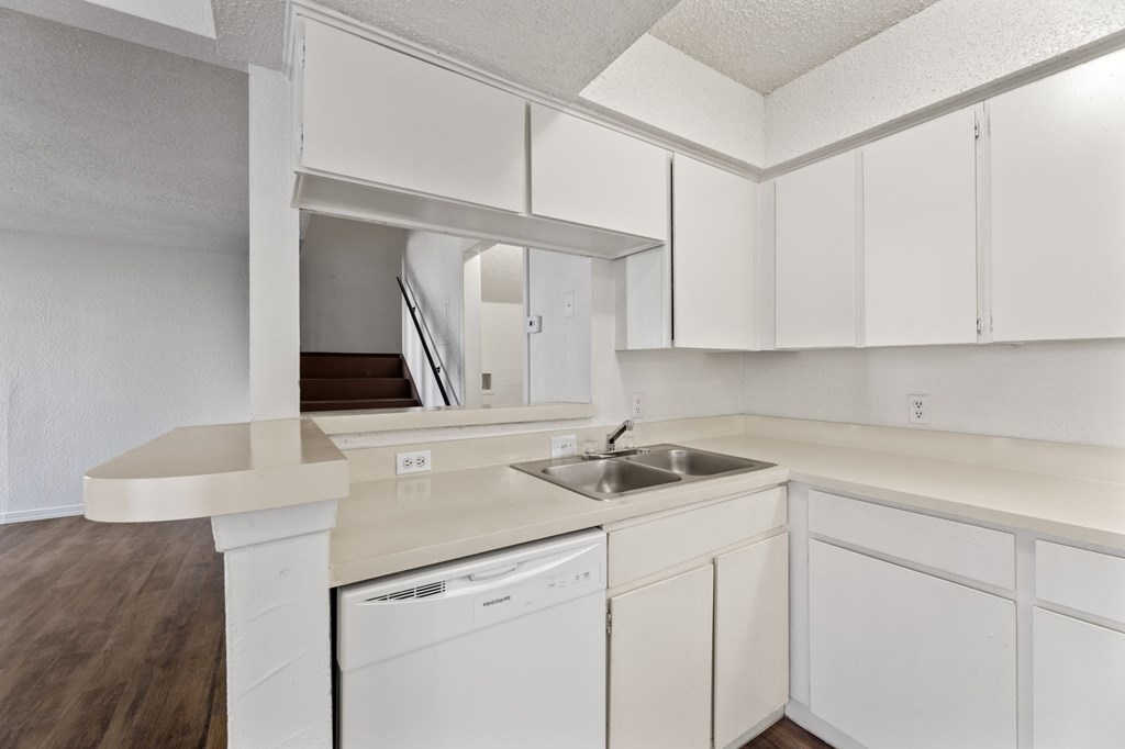 A white kitchen with a dishwasher and sink.