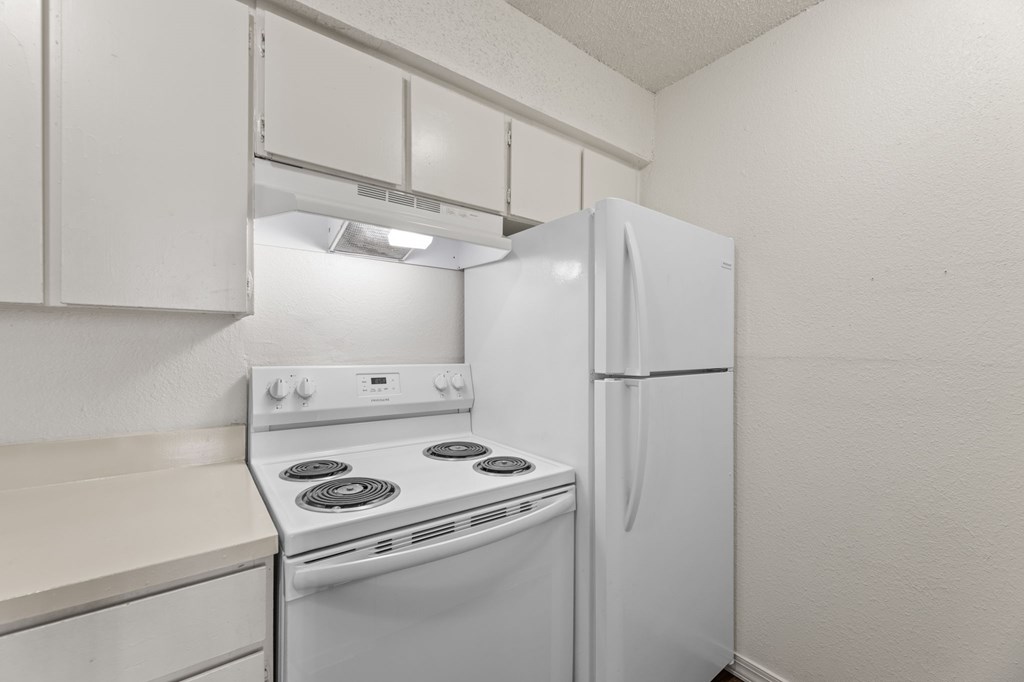 A white kitchen with a stove and refrigerator.