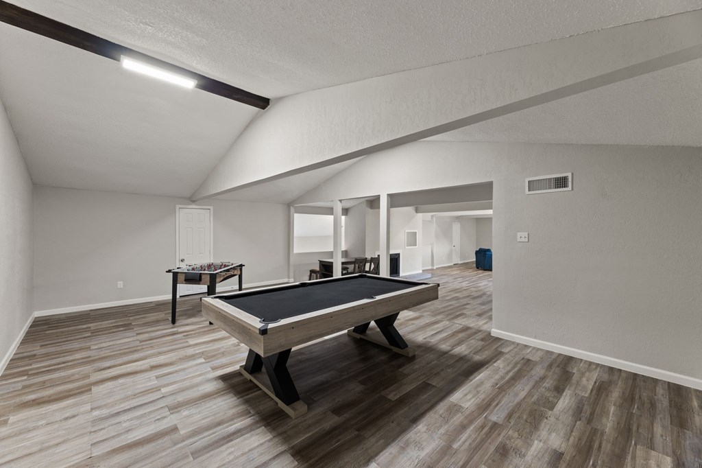 A pool table in a room with wooden flooring.