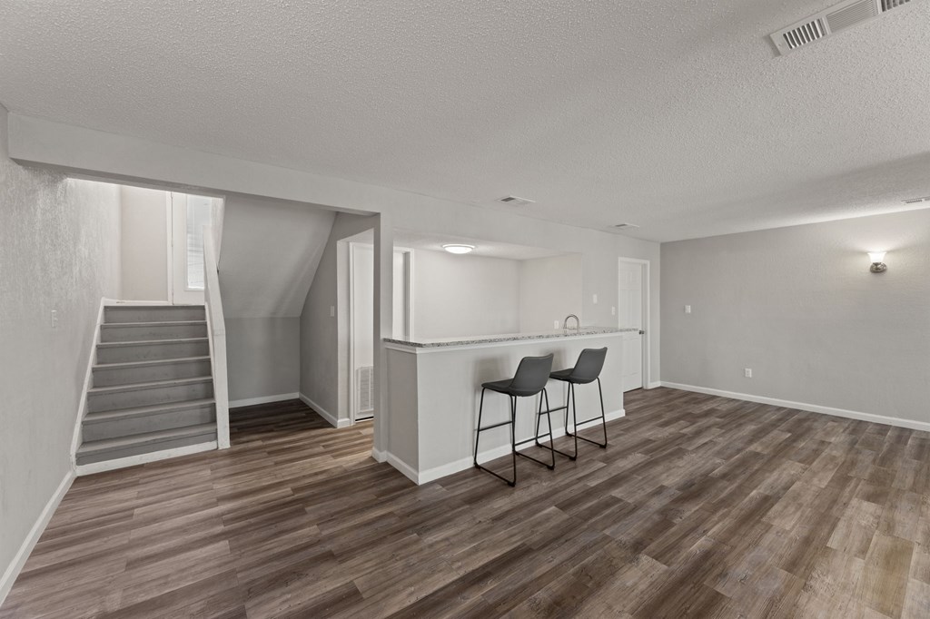 A room with wooden flooring and a staircase.