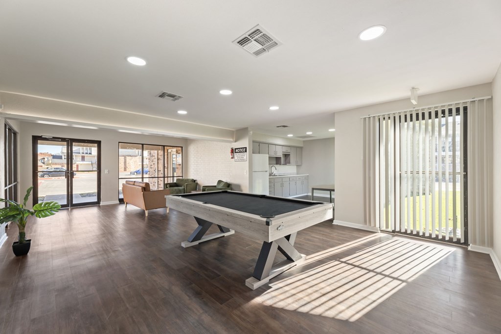 A room with a pool table and a plant.