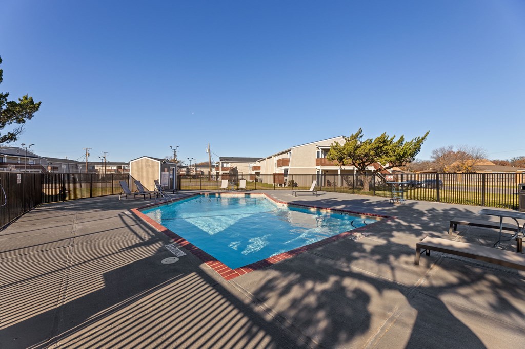 A swimming pool surrounded by a fence and trees.