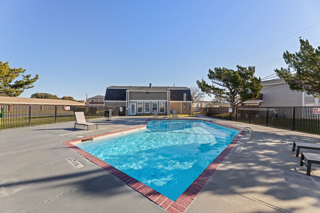 A small pool with a red border and a building in the background.
