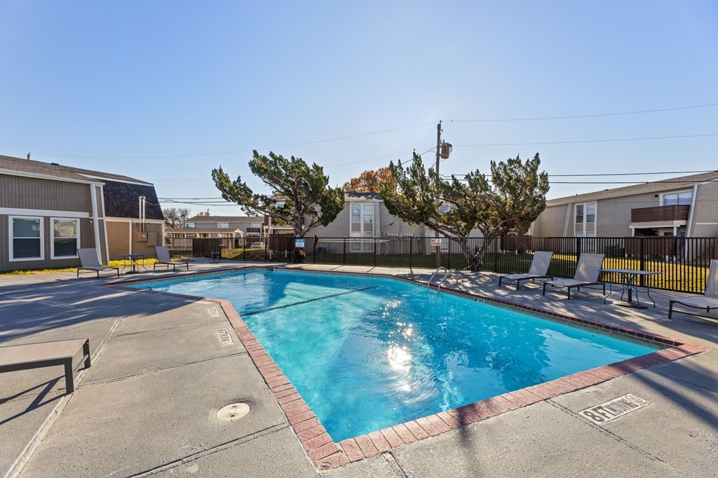 A swimming pool surrounded by a fence and chairs.