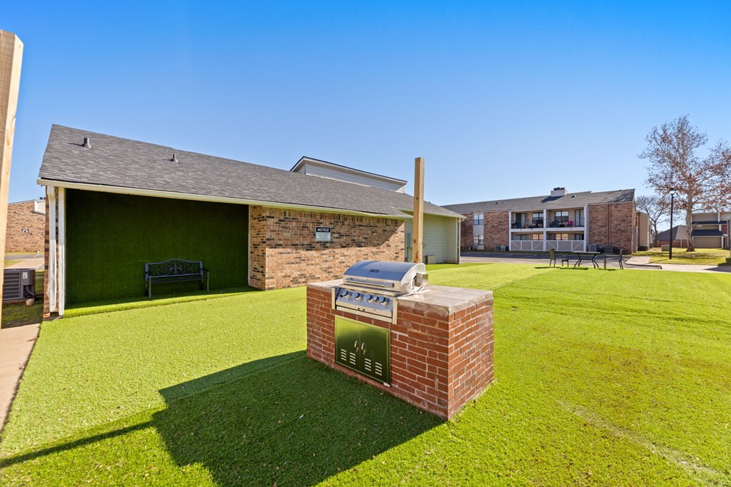 A brick mailbox sits on a green lawn in front of a house.