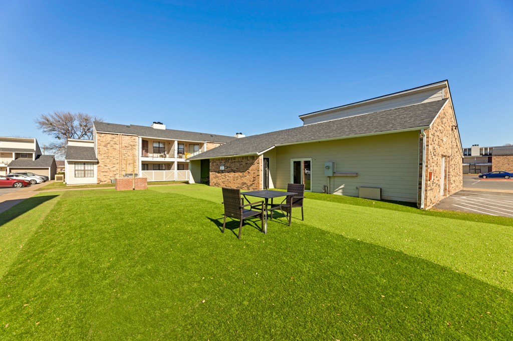 A lawn with a bench in front of a building.