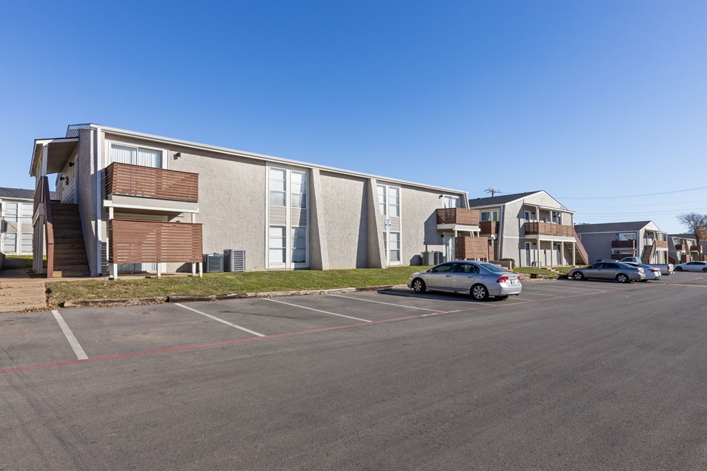A parking lot with cars and apartment buildings in the background.