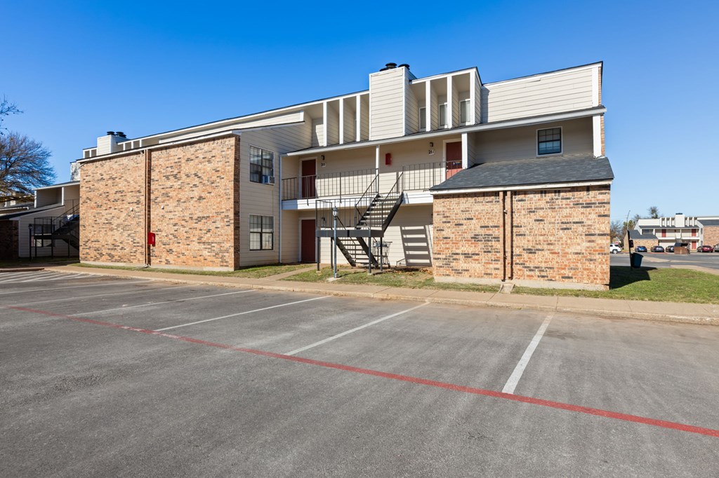 A parking lot in front of a two-story building with a brick facade.