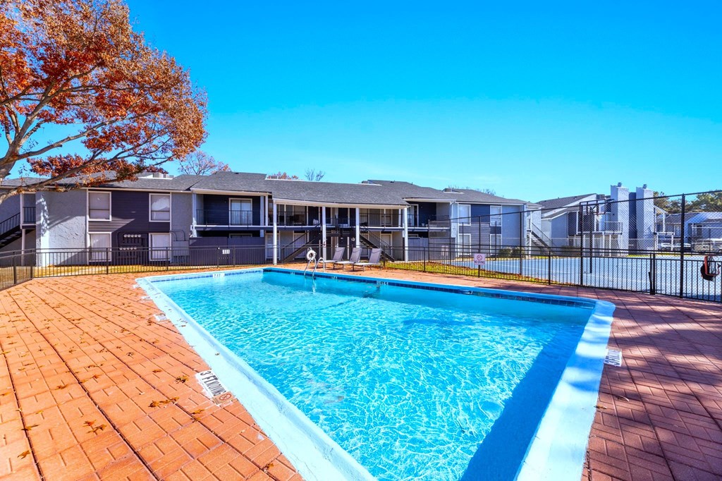 A swimming pool surrounded by a fence and trees.