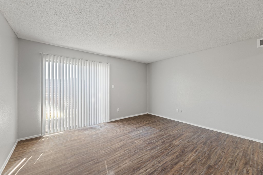A room with wooden flooring and a window with blinds.