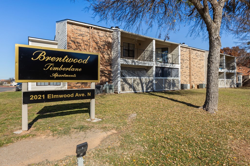 A sign for Brentwood Timberlane Apartments stands in front of a building.