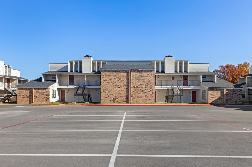 A parking lot in front of a building with a clear blue sky.