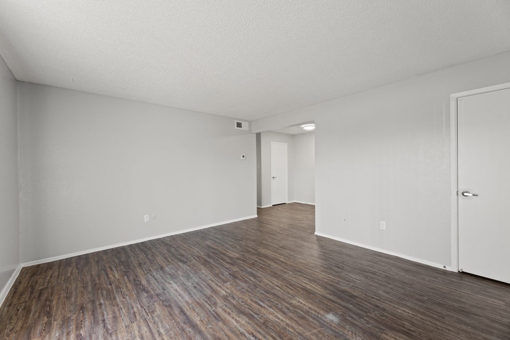 A room with wooden flooring and white walls.