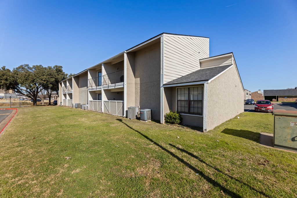 A modern building with a flat roof and a parking lot in front.